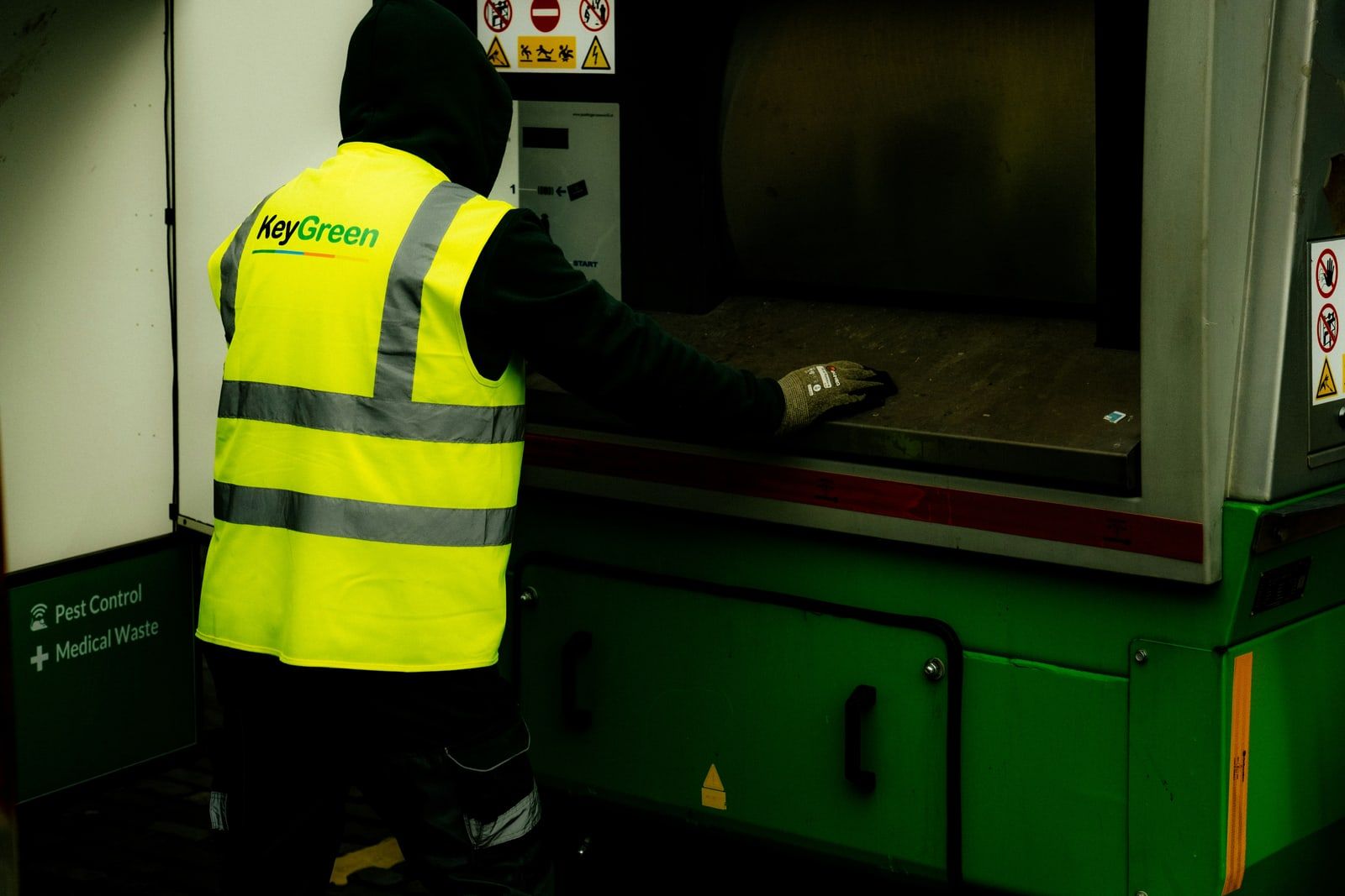 Operative in a hi-vis jacket loading a waste processing machine